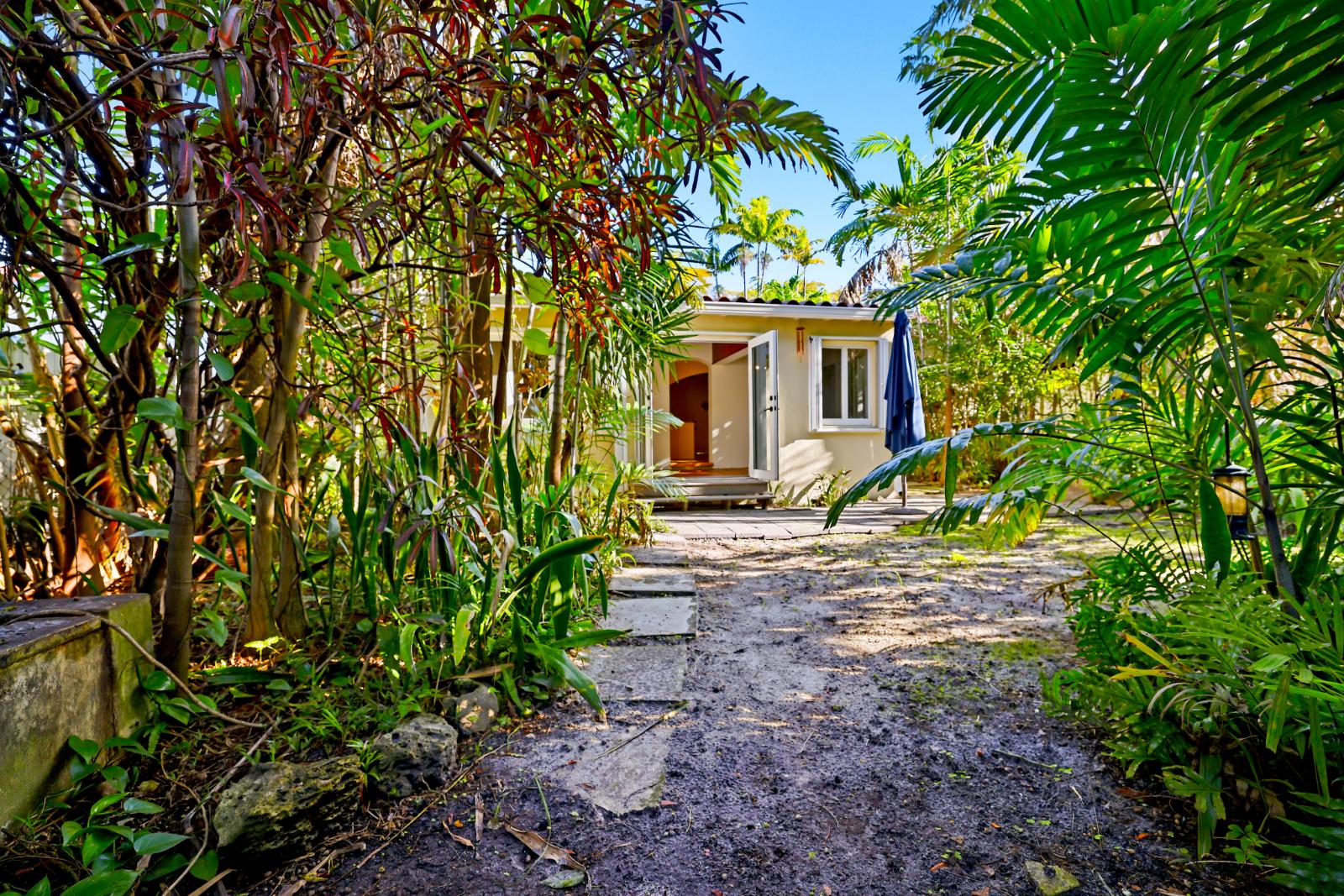 Backyard path view toward the house framed by lush tropical landscaping