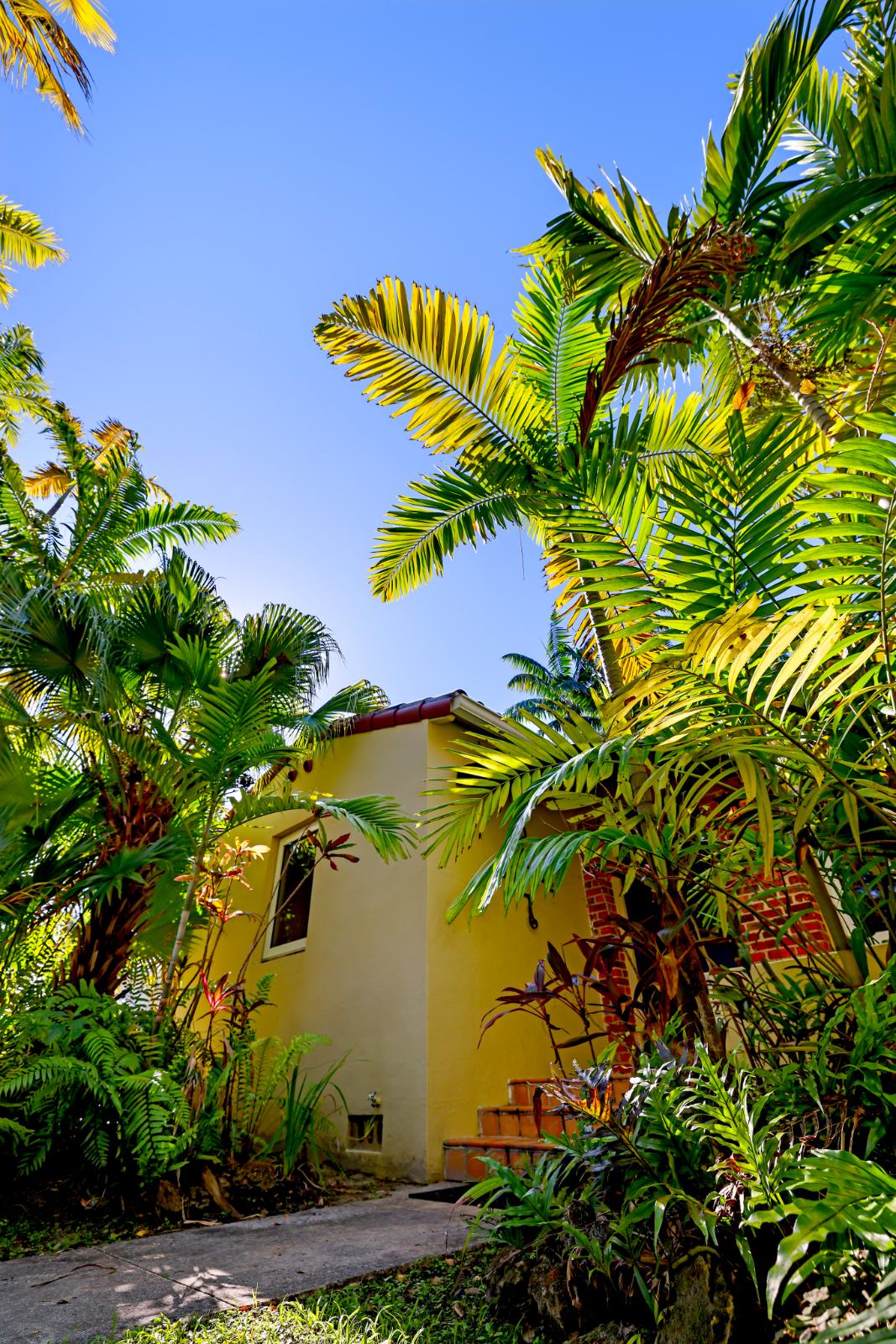 Garage-side exterior view with mature landscaping